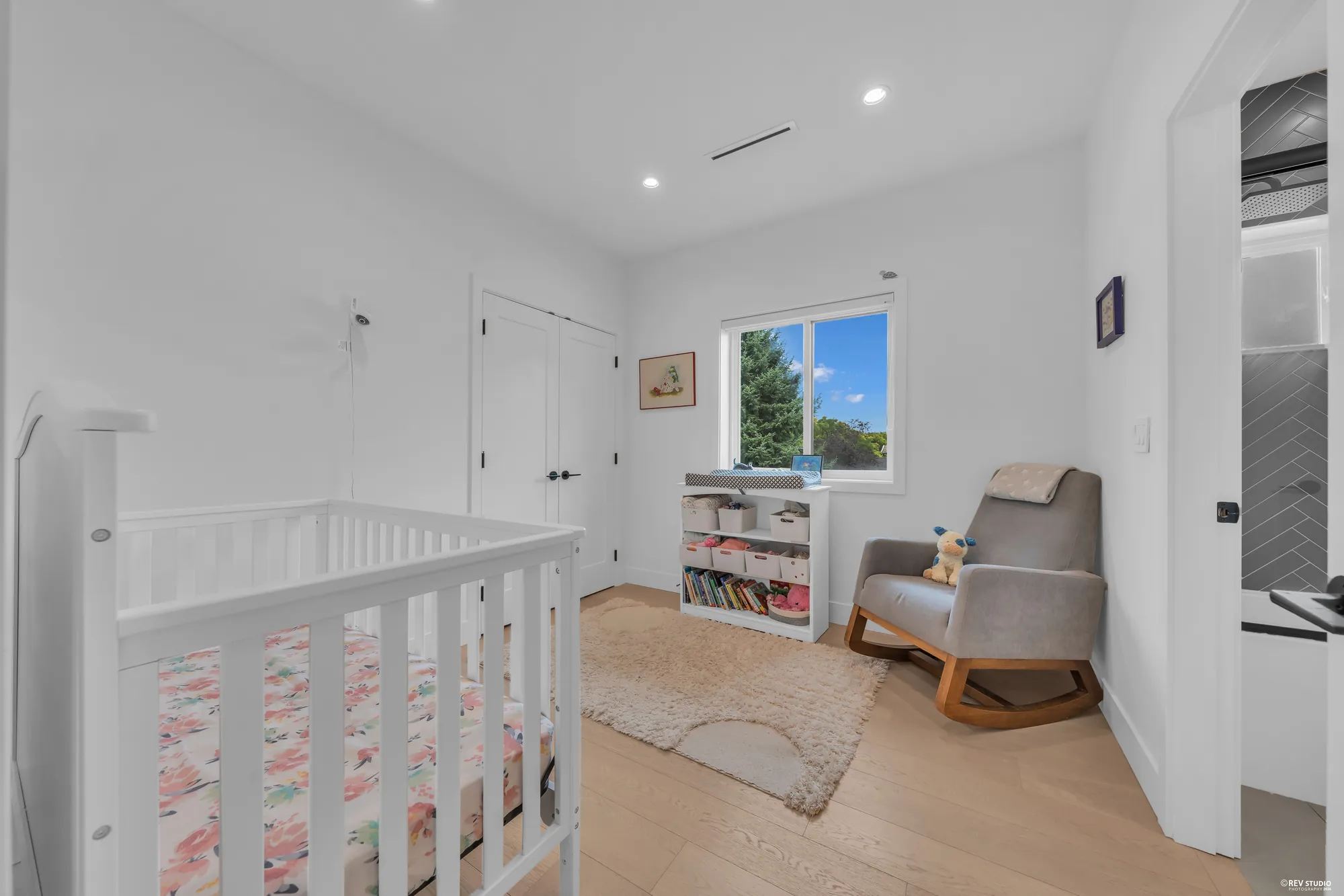 The third bedroom with a crib, a rocking chair and a window