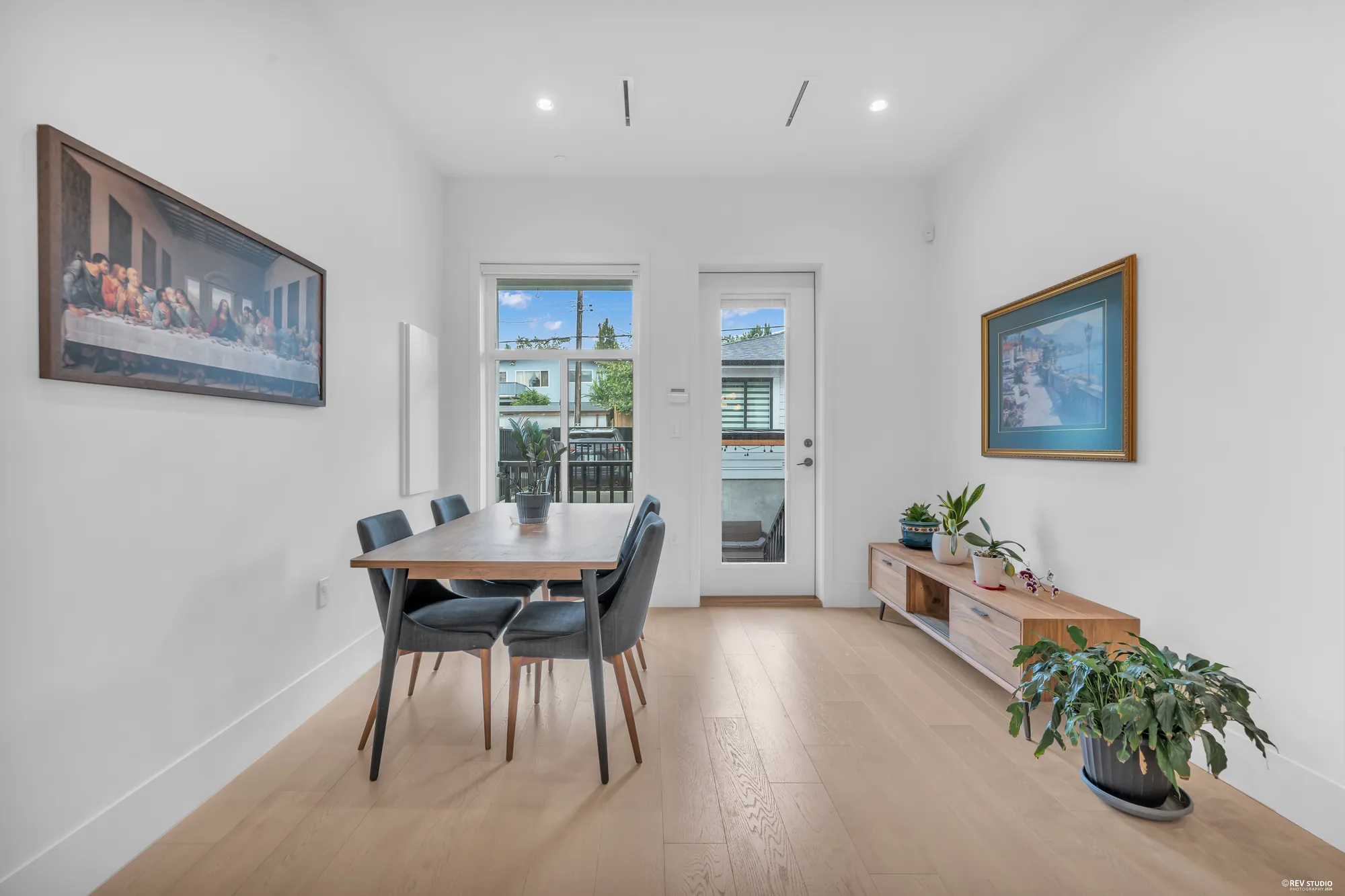 The dining room: a wooden table with blue chairs, a glass door to the deck with windows either side
