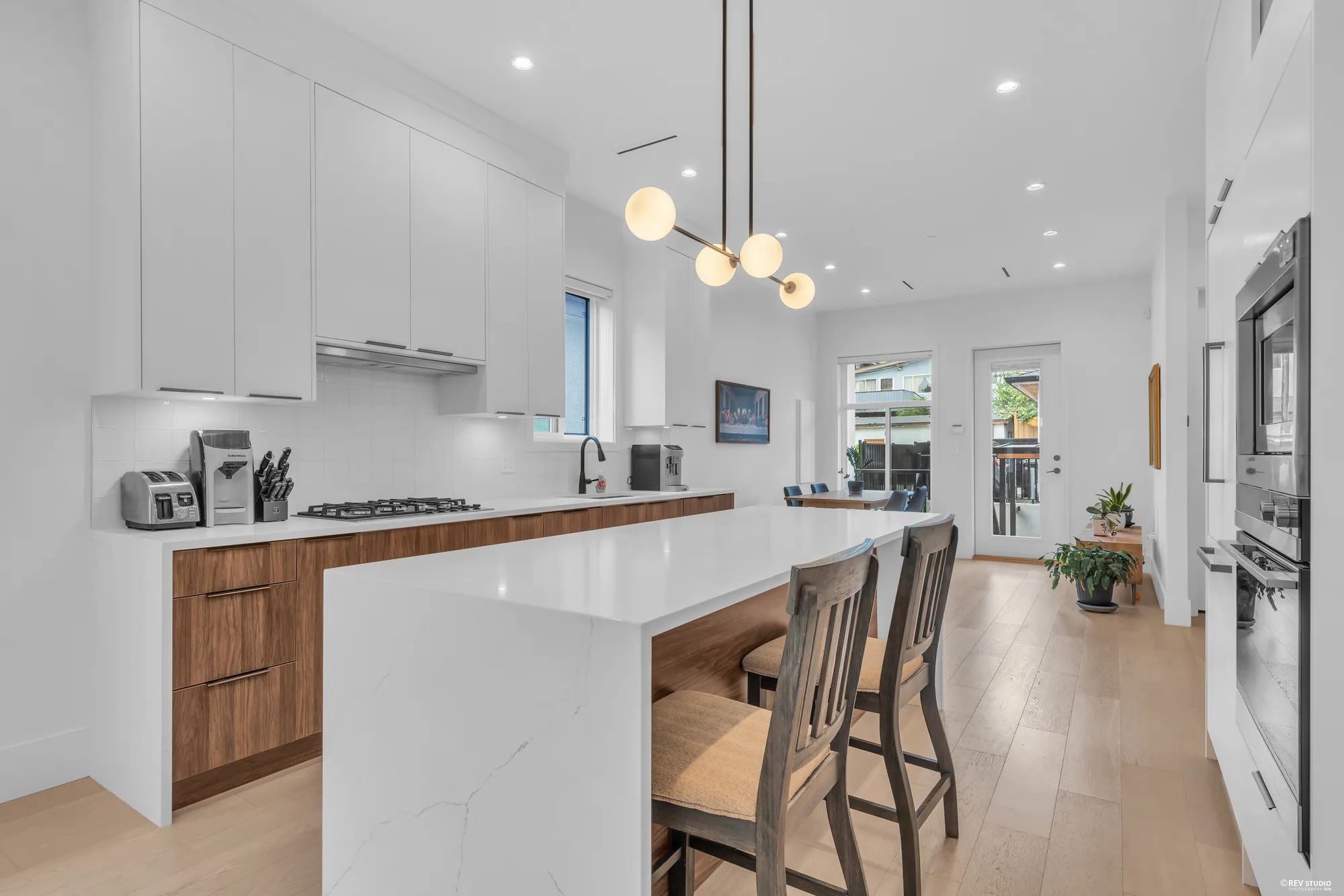 The island with three stools, the range and the hood beyond