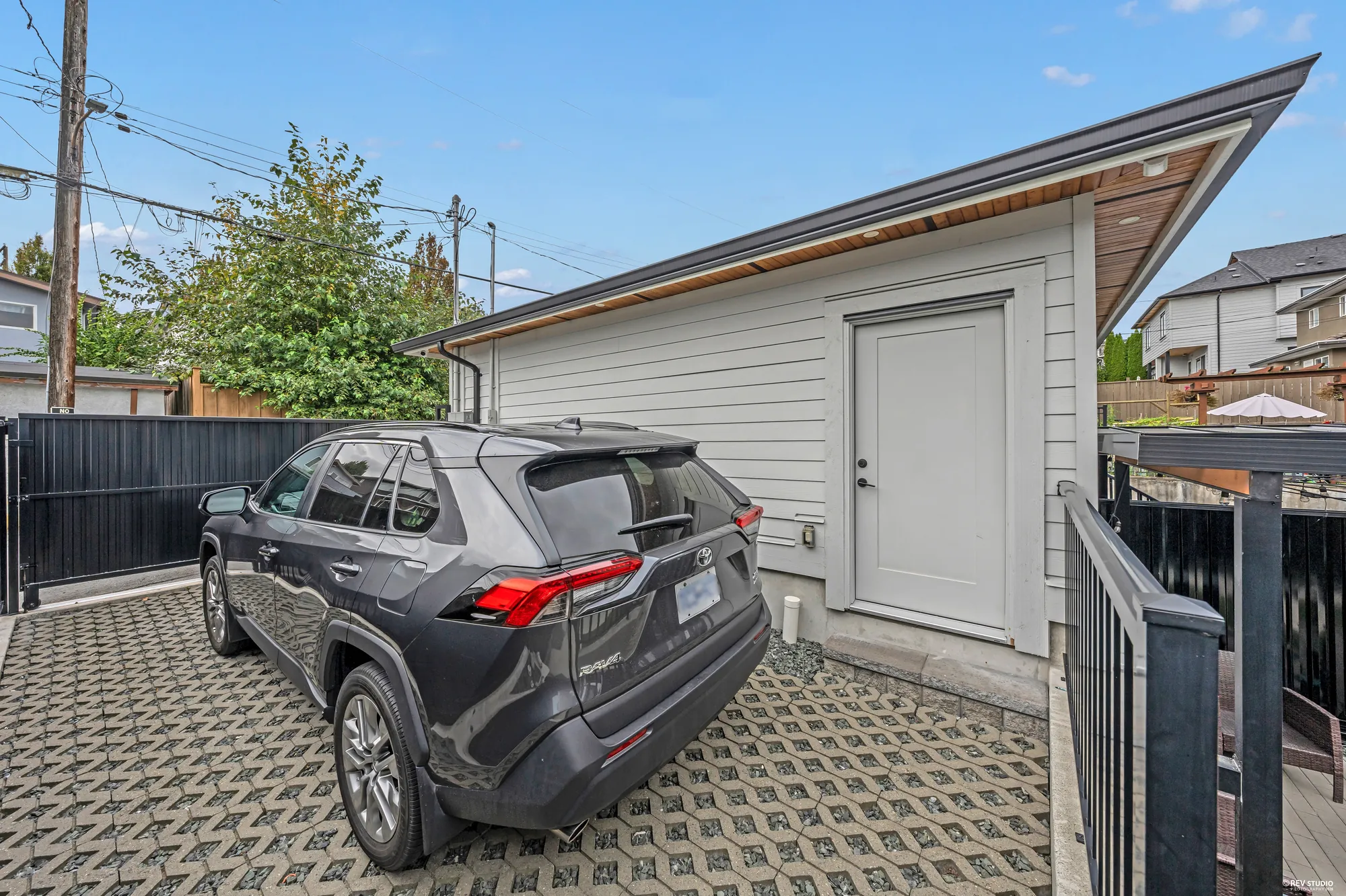The parking pad in front of the garage, paved in a permeable grid, a car parked on it