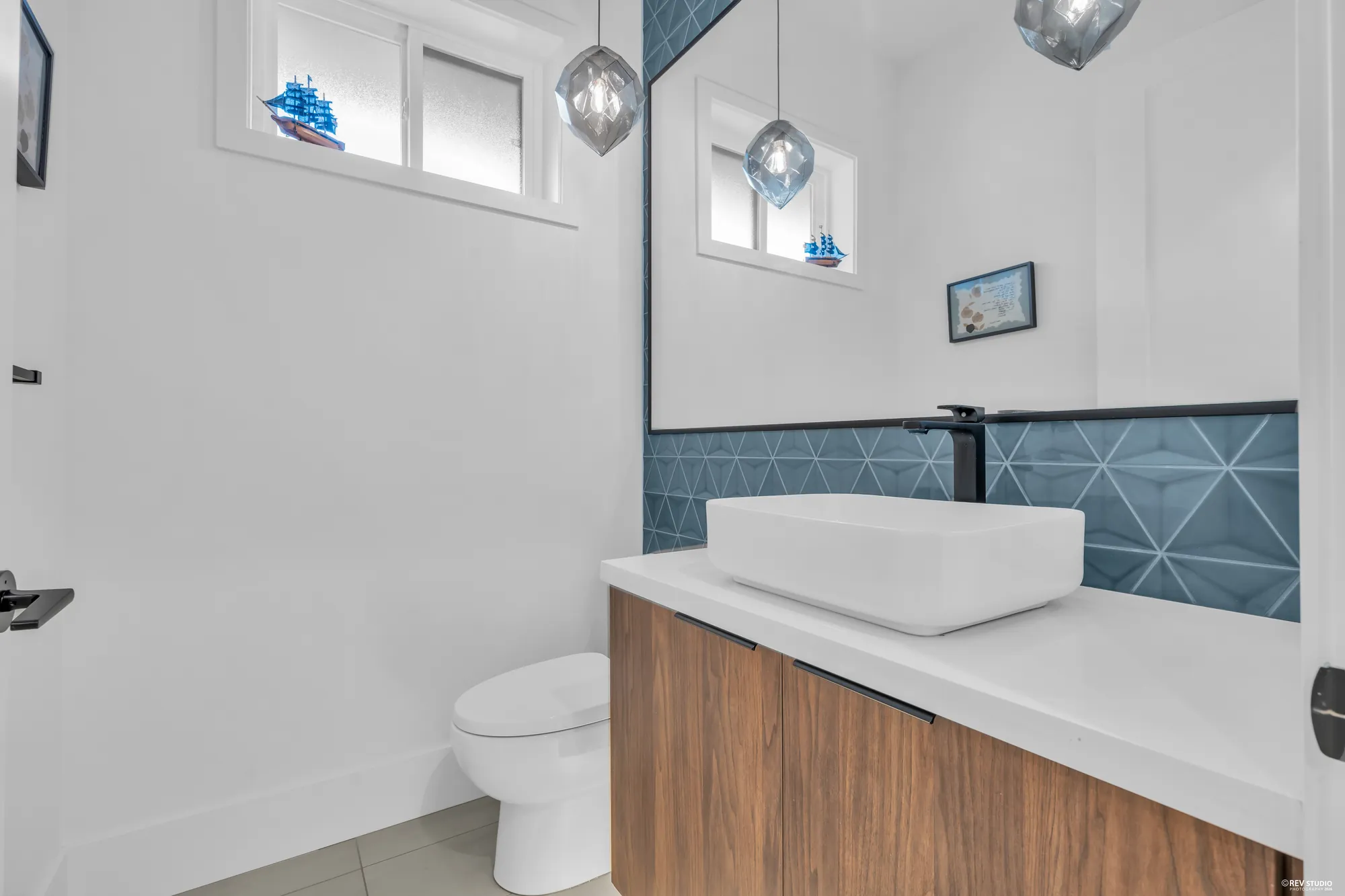 The powder room: a vessel sink on a walnut vanity, a teal tiled splash, two small glass pendants